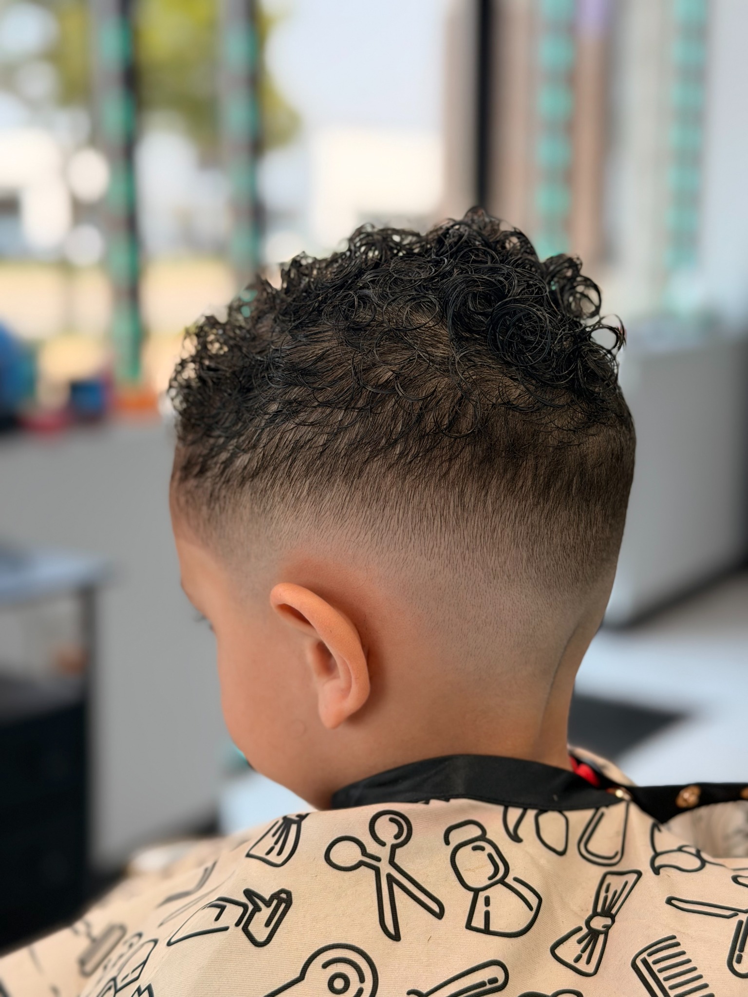 Kid's haircut with a smooth fade and curly top